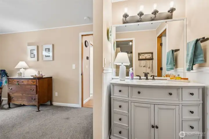 Function meets a little flair in this thoughtfully arranged primary bath. The vanity area sits separately, framed by classic beadboard detail and a furniture inspired cabinet that feels more boutique than builder basic. The undermount sink and waterfall fixture give it a subtle upscale vibe, and there is plenty of elbow room for daily routines. The shower and toilet are tucked into their own private zone, which makes coexisting schedules much easier to manage. With the walk in closet right nearby, the whole sequence of getting ready actually feels streamlined, like someone really thought through how this space would be used.