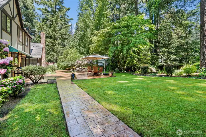 Concrete pathway connects patio to garage and utility shed