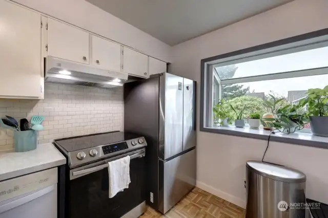 Open design kitchen with induction stove. Notice the bay window that works as a greenhouse