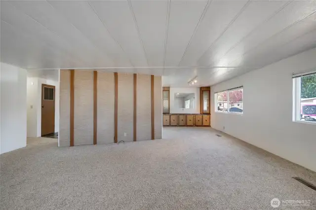 This wrap-around layout flows from Living Room to the dining area and Kitchen. The hallway entrance to the bedrooms and bathrooms is on the left of the picture.