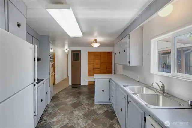 A great Kitchen layout features a dishwasher, refrigerator, counter-top stove, and double-oven!