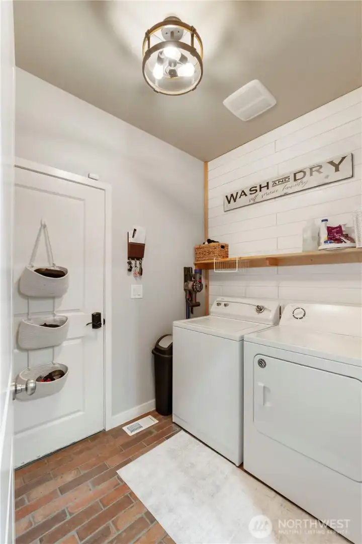 Large utility room with ship lap & faux brick flooring.  Washer & dryer to stay!