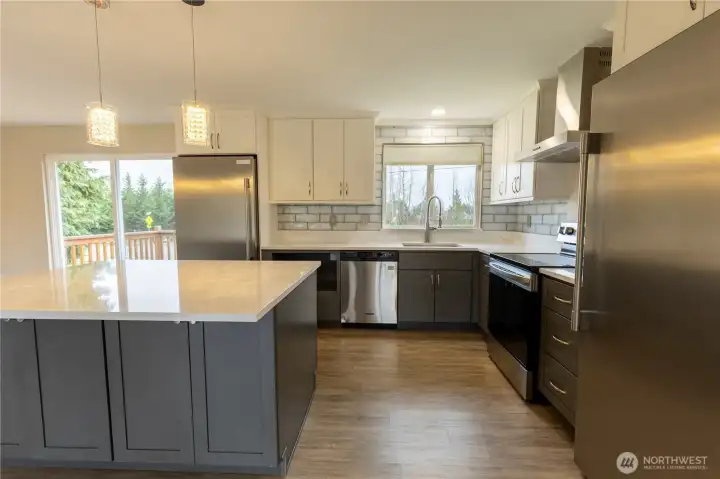 Kitchen with large island and quartz counter tops. Separate full sized refrigerator and freezers. Stainless steel appliances. Lots of cabinet storage space.