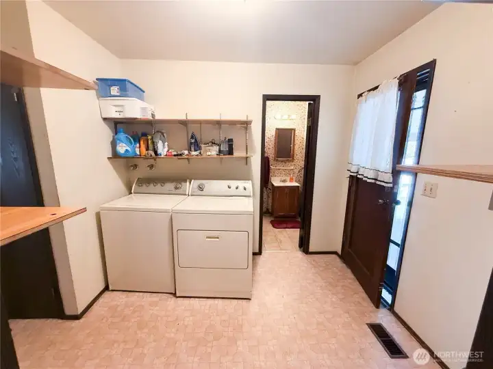 Utility room w/lots of shelves for storage & door to back covered patio & carport