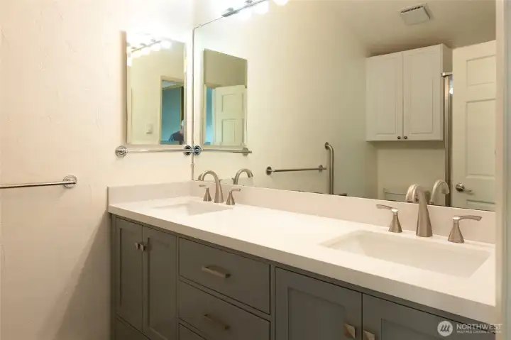 The beautifully updated en-suite bath features a custom double vanity with solid-surface countertops, contemporary fixtures, abundant cabinetry, and a beautifully remodeled three-quarter shower, offering the comfort and convenience expected in a luxury waterfront residence. The beautifully updated en-suite bath features a custom double vanity with solid-surface countertops, contemporary fixtures, abundant cabinetry, and a beautifully remodeled three-quarter shower, offering the comfort and convenience expected in a luxury waterfront residence.