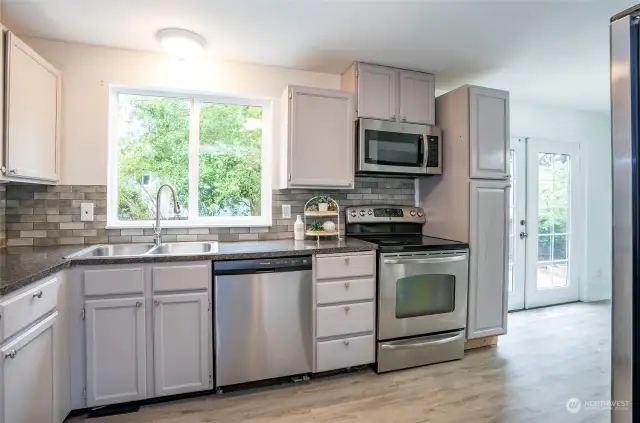 Modernized with stylish stainless steel appliances, the kitchen boasts an oversized window offering a delightful view of the backyard.