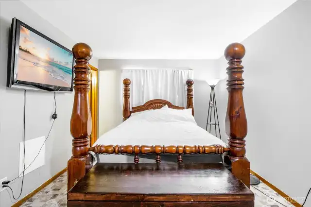 Just a floor lamp brightens up the primary bedroom with it's light grey tones on the wall, matching the flooring.