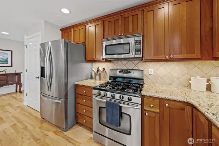 This section of the kitchen features a full suite of stainless-steel appliances, including the Whirlpool French-door refrigerator and Maytag gas range.