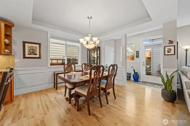 The dining area feels bright and welcoming, framed by chair-rail trim and elegant shadow-box wall detailing that add depth and sophistication. The exterior door leads out to a private patio, bringing in natural light and creating an easy indoor-outdoor connection for everyday living.