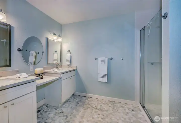 Spa-inspired primary bath spotlighting dual sinks, dressing table, bidet, and large, sleek shower.