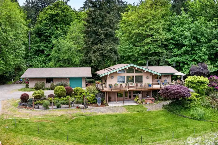 Note the 3-car garage with shop space to the left, and just below it, the vegetable garden. The lower level has its own entrance and access to the hot tub that stays. The expansive deck is the perfect place to relax or entertain.