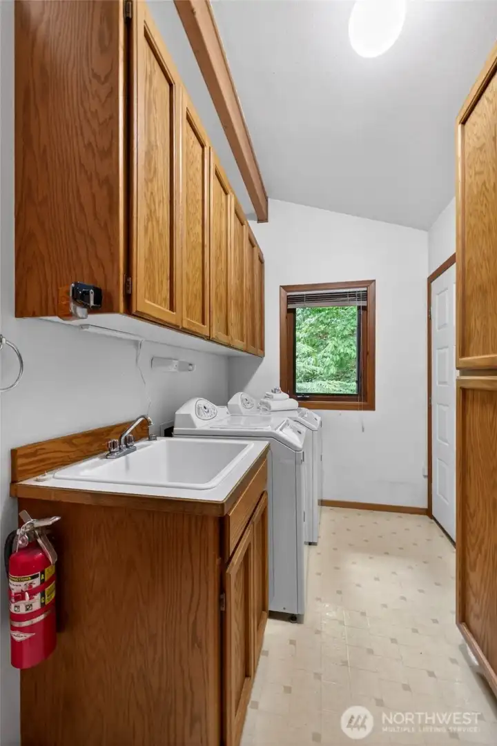 The large laundry room has a laundry sink, ample storage, and a door to the back deck. The washer and dryer stay.