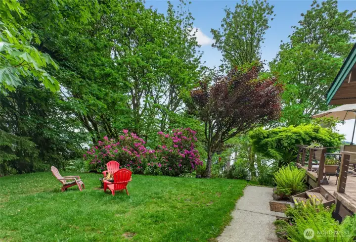 This is the lush side yard, currently set up with fire pit and Adirondack chairs.