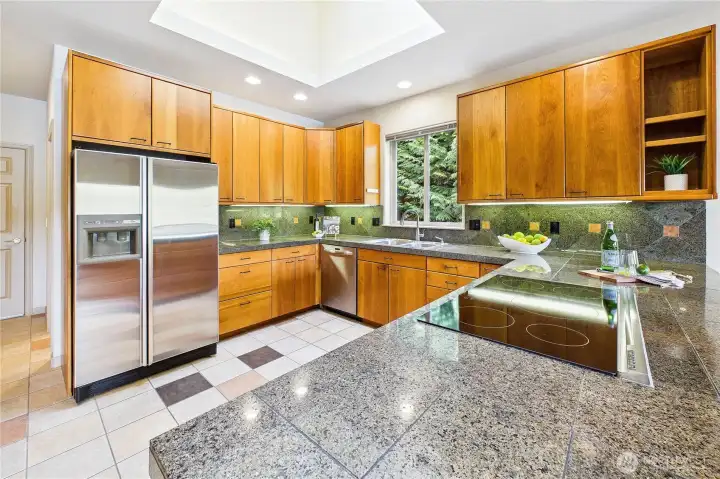 The kitchen features granite tile, a new induction cooktop, a newer Kitchen Aid dishwasher, and extensive custom cherry cabinets.