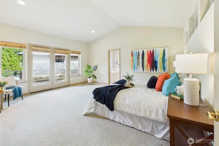 The spacious primary suite with French doors to the private balcony and en-suite bath and closet beyond.