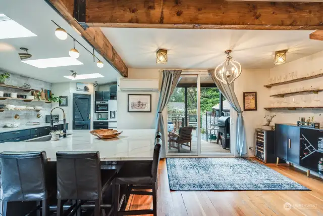 View from Living room to Dining room and Kitchen. Deck beyond sliding doors.