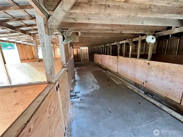 Interior barn hallway with 8 well-laid-out stalls—4 for horses or large animals, 4 ideal for goats or sheep.