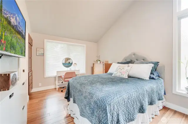 Primary bedroom filled with natural light and vaulted ceiling.