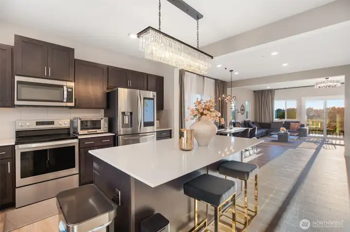 Welcoming island kitchen with stainless steel appliances and quartz counters.