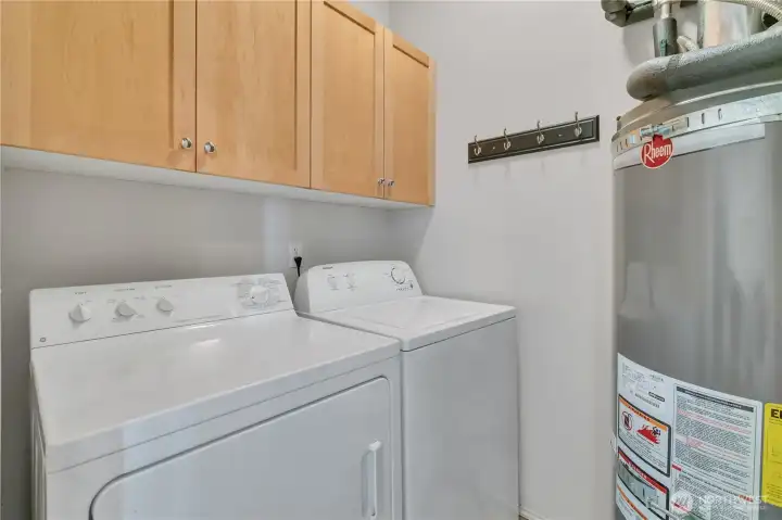 Utility room includes washer and dryer along with the water heater.