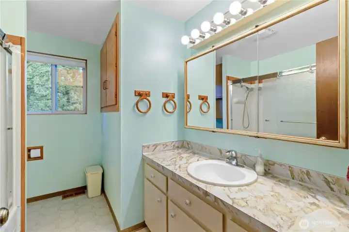 Upstairs full bathroom w/ long vanity, built-in storage & tub/shower combo.