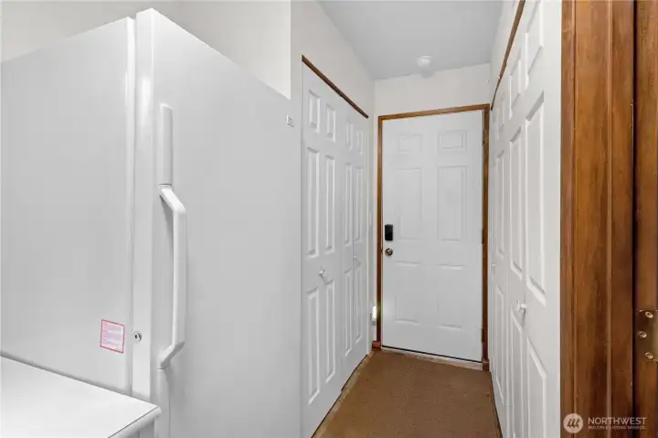Hallway from laundry area leading to the attached two-car garage w/ additional storage closets.