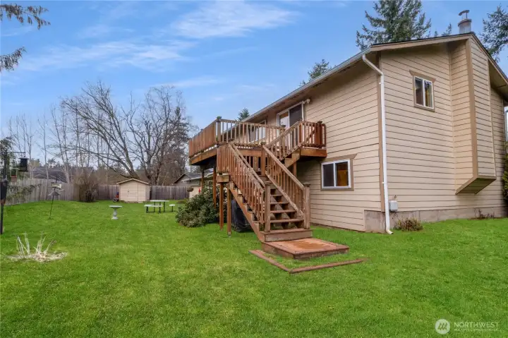 View of the backyard featuring the elevated deck & stair access to the yard.