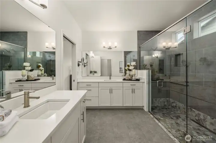 The stunning spa like primary bath with dual vanities, Quartz counters, tile floors and extra-large fully tiled shower with double shower heads and bench seat.