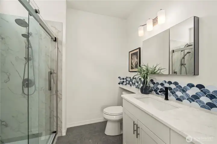 Guest bath with a stunning shower, Quartz counter and decorative glass backsplash, custom mirror/medicine cabinet.