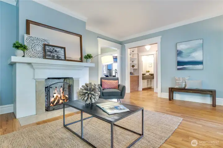 Oak hardwoods extend from the fireside sitting area into the bedrooms, hall, and dining room. Notice the opening into a 3/4 bath. A pocket door can be closed to create the feeling of a private suite with the bathroom, front bedroom, and linen storage.