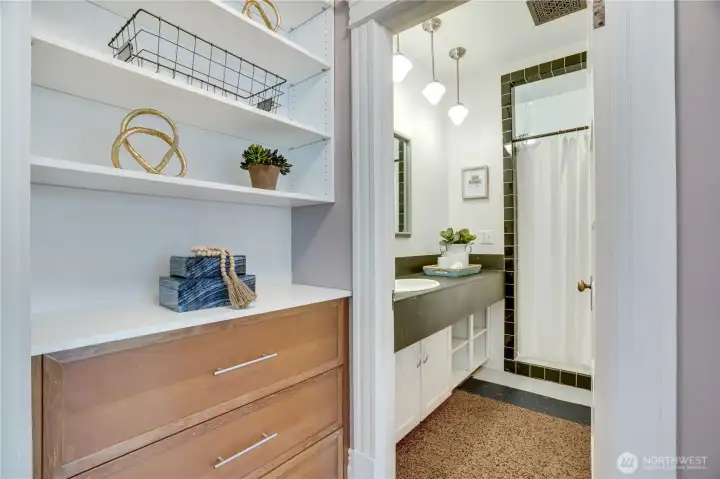The apartment offers good storage options including this built-in for linens. The 3/4 bath includes a tiled shower stall, pendant lights, and cabinets under the vanity.
