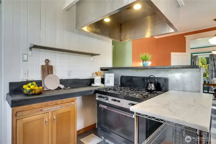 Concrete countertops, stainless sinks, and a commercial-style hood vent, provide contrast to the turn-of-the-century elegance of the other rooms, while pendant lights and simple white walls bring light.