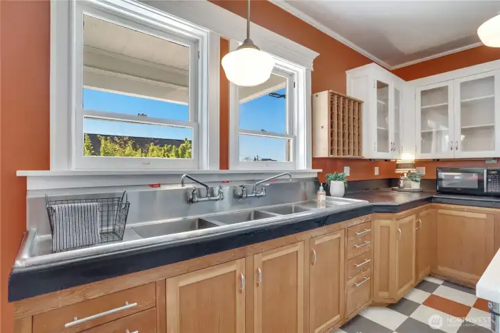 Three stainless sink basins are set into the concrete countertops and windows look northwest over the deck and neighborhood.