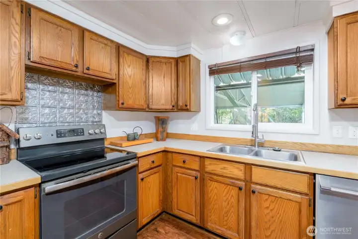 Gather, cook, and connect in this inviting kitchen where warm oak cabinetry, abundant counter space, and updated stainless steel appliances create a space that's as functional as it is welcoming. The large window above the sink fills the room with natural light and offers a view of the covered outdoor living area, making everyday tasks feel a little brighter. With generous storage, ample prep space, and timeless finishes, this kitchen is ready for everything from weeknight meals to holiday gatherings.