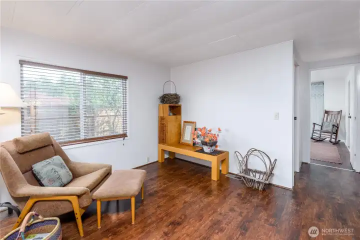 Versatile and inviting flex space filled with natural light from a large picture window overlooking the fenced backyard. Warm wood-tone flooring and a neutral color palette create a comfortable setting ideal for a reading nook, home office, hobby area, or additional sitting room.