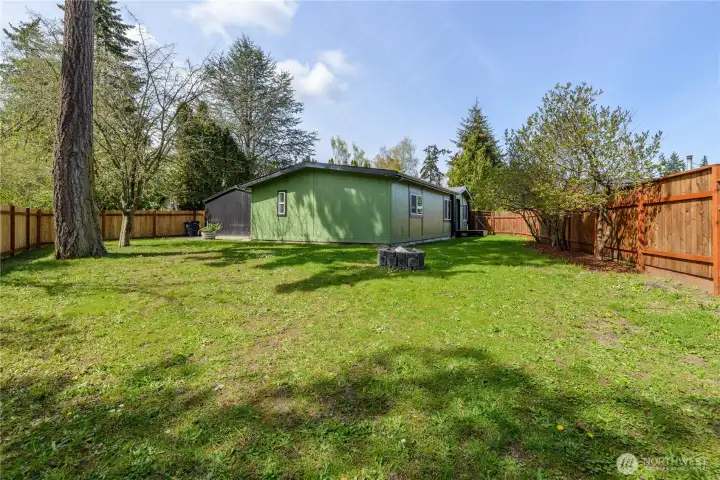 Spacious, fully fenced backyard offering room to relax, entertain, garden, or play. Mature trees provide shade and privacy, while the open lawn creates a versatile outdoor living space. Enjoy evenings around the fire pit, gatherings with friends and family, or simply taking in the peaceful setting. A detached storage shed adds convenience for tools, equipment, and seasonal storage.