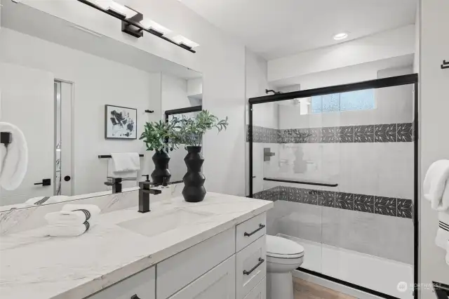 lower level bath with fully tiled shower & glass doors, quartz counters & extra drawers.