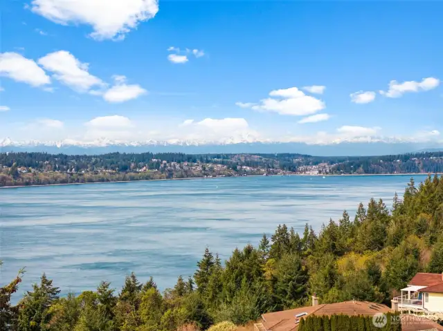 A breathtaking view of the Olympic Mountains rises just behind the mouth of Gig Harbor, offering a majestic backdrop that enhances the beauty of this remarkable location.