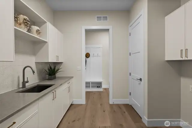 Conveniently located on the main floor near the primary suite, this laundry room boasts sleek cabinetry and quartz countertops, combining functionality and style for effortless organization.
