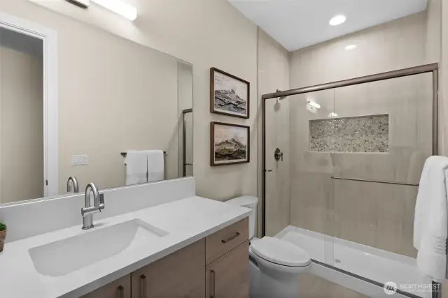 The downstairs guest bathroom features a stylish tile surround with a convenient niche, while the high ceilings create an open, airy feel that enhances the space's brightness.