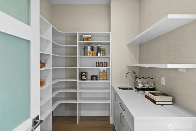 Spacious butler’s pantry featuring generous storage, a sleek sink, and a stunning full-height tile accent wall.