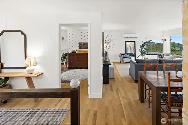 Select grade white oak hardwood flooring throughout main floor. View from primary bathroom looking toward living room and upstairs guest bedroom