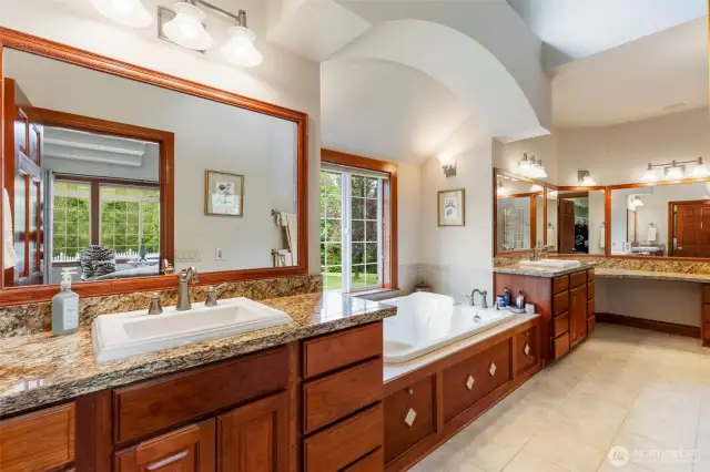 Primary en suite bathroom provides two separate vanities, jetted soaking tub and  glass block enclosed shower.