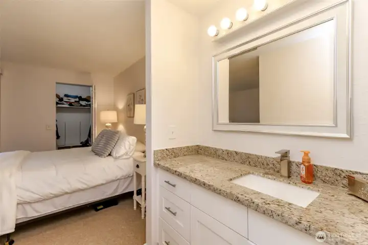 Large primary vanity with granite countertop and loads of personal storage space.