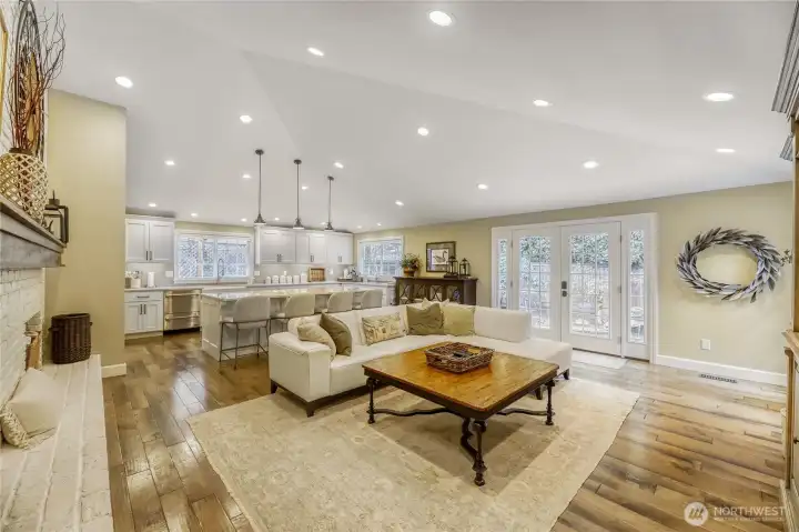 Family room with brick gas fireplace. French doors leading to patio. View of kitchen and large island for entertaining.
