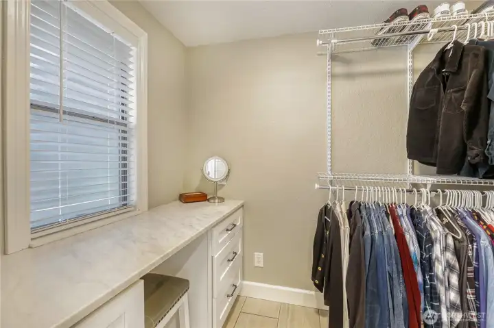 Walk in closet has vanity area with additional cabinets for storage.