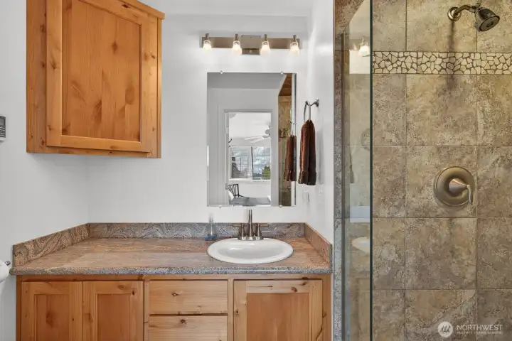 Primary bath with granite counter, tile floor,, & tile and stone shower.
