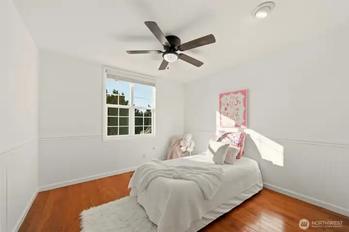 Bright bedroom featuring wainscoting detail and an oversized window.