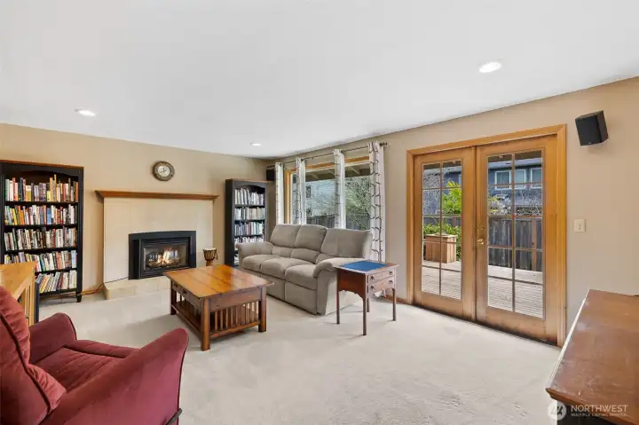 Large family room with gas fireplace, and French doors leading to deck.