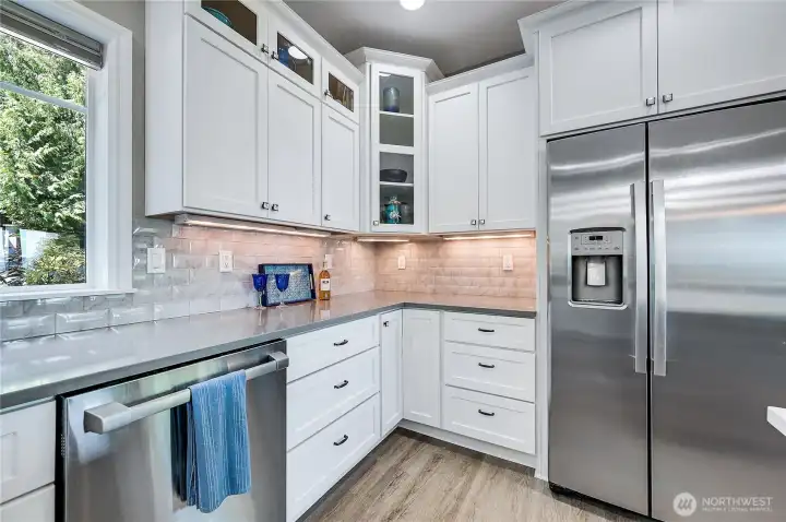 The gray quartz counters tie in perfectly with the stainless appliances. The glass front cabinets add a classy touch.
